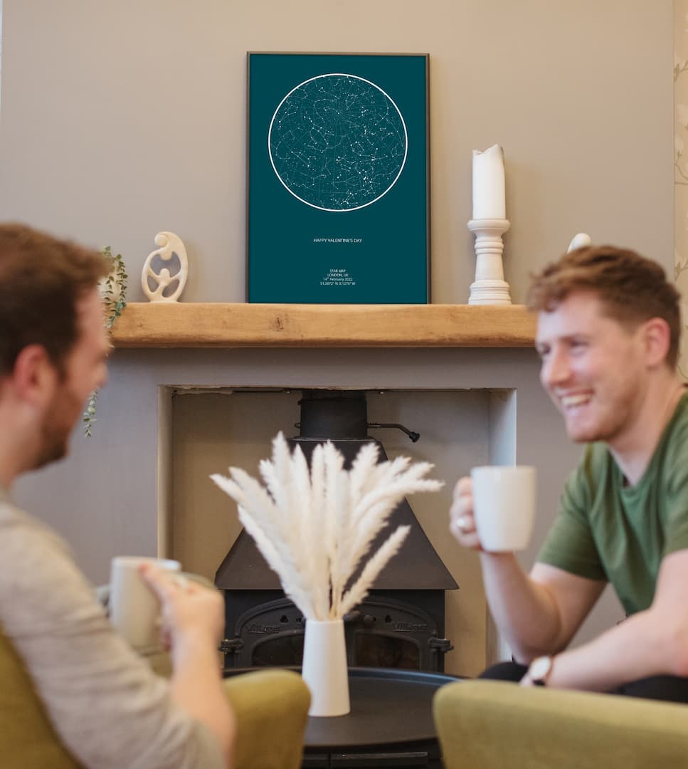 Two men sitting in chairs with a framed picture of the night sky behind them